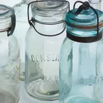 Oil painting of 4 clear glass vessels on white table cloth on linen