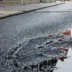 View from ground of puddle on Collister street reflecting grey sky