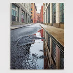 View from ground of puddle on Collister street reflecting grey sky