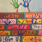 Painted hands above boxes in blue and green with prints all over boxes