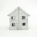 Wooden cabinet shaped like a house with metal cast on the front