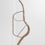 installation view of a spindly bronze sculpture mounted to the wall