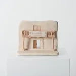 ceramic piece depicting a building facade with a banner reading "Campaña gratuita"