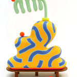 Chiaozza paper pulp sculpture of abstract yellow and blue vase with comb-like green plant on small wooden table base