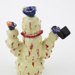 Jen Dwyer sculpture - beige cactus with red accents and one eyeball at center, holding black laptop and other accessories