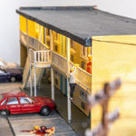 miniature diorama by Abigail Goldman of a woman bleeding on the ground in the parking lot of a motel