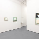 white gallery wall with four paintings in blue, black, and warm tones
