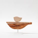 Wooden sculpture of a bird on a boat shaped object by Hyland Mather
