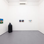 white gallery walls with paintings of various sizes and a black pedestal with a sculpture in the corner