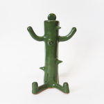 ceramic piece by Jocelyn Tsaih of tsall green figure sitting with cactus like thorns coming out of it