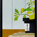 framed cropped painting of a green leafy plant sitting on top of books with a light blue background
