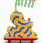 Chiaozza paper pulp sculpture of abstract yellow and blue vase with comb-like green plant on small wooden table base (alternate view)