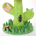 Lorien Stern's ceramic sculpture of an orange flower with grass and bugs