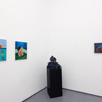 white gallery walls with paintings og various sizes and colors, and a black pedastal with a house sculpture