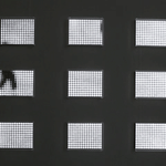 Gif of a spread out grid of nine rectangular pieces with white LEDs behind Plexiglass. The LEDs display black and white scenes of shadowy figures walking around Grand Central Terminal in New York City