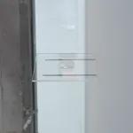 Side view of an engraved reading lens resting on a glass panel, which rests on two horizontal graphite pegs.