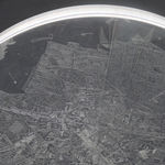 Detail of a clear convex disk with etchings set on a dark grey background.