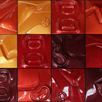 Three-by-four grid of reflective red and orange toned squares with low relief depictions of automotive and anthropomorphic close-up scenes.