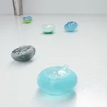 Five glass blown sculptures arranged on a white floor.