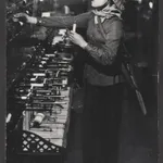 A worker in Textile factory in the city of Nam Dinh. Nam Dinh, once Vietnam’s third largest city, has been almost completely evacuated because of recent bombings. This factory, the country’s second largest textile plant, has been largely evacuated into rural areas. In the small part of the factory still operating in the city, workers wear militia uniforms with rifles slung across their backs to be used against American aircraft in the event of the attack