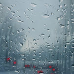 An out of focus painting of a river with bare trees on either side and a bridge intersecting it with red lights across it, seen through a glass screen with water droplets scattered across it, seen through a glass screen with water droplets scattered across it. By artist Esther Nienhuis.