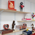 wooden shelves on a white wall with objects like books and robot sculptures on them