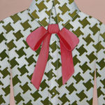 painting of a woman wearing a white and green patterned button up shirt, with a pink bow by Angela Burson
