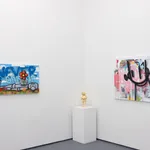 corner of a room with white walls with a gold statue on a padastal in the middle and larger paintings on each side