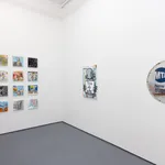 corner of gallery with white walls with a grid of colorful pieces on the left and two larger colorful pieces on the right