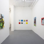 wide angle image of a gallery room with white walls with one painting on the left wall, two piantings on the right wall, and a grid of smaller paintings in the middle