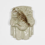 image of a cream sculptural mask with a line of sand across its face