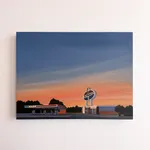 Kristin Moore AMOCO Sunrise painting featuring a vintage AMOCO gas station with canopy and signage set against a soft pastel sunrise sky. Hanging on a white wall
