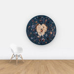 Blue velvet tondo with hands in the middle holding a dung beetle, surrounded by archeological objects hung on wall for scale