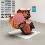 Wooden sculpture shown amongst other artwork in gallery