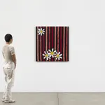 Scale of figure standing near striped needlepoint painting with daisys against white wall