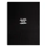 A vertical black and white typographic painting featuring the hand-painted text "I WAS NEVER YOUR ENEMY" with "NEVER" struck through, and the word "LOVER" emphasized at the bottom against a dark, textured background.