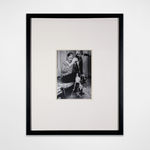 Framed black and white photograph of Andy Warhol soaked and emptying his boot full of water onto the ground