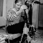Black and white photograph of Andy Warhol soaked and emptying his boot full of water onto the ground
