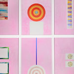 An array of colorful paintings comprised of geometric abstract forms displayed on a white wall