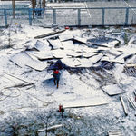 Photo of scattered pieces of wood covered in snow with a person in the centr