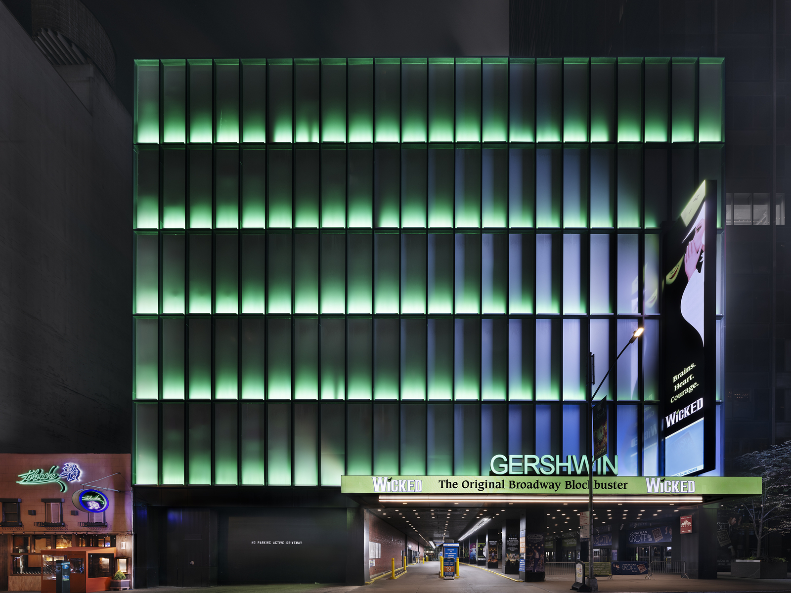 The outside of the Gershwin Theatre at night, with green lighting.