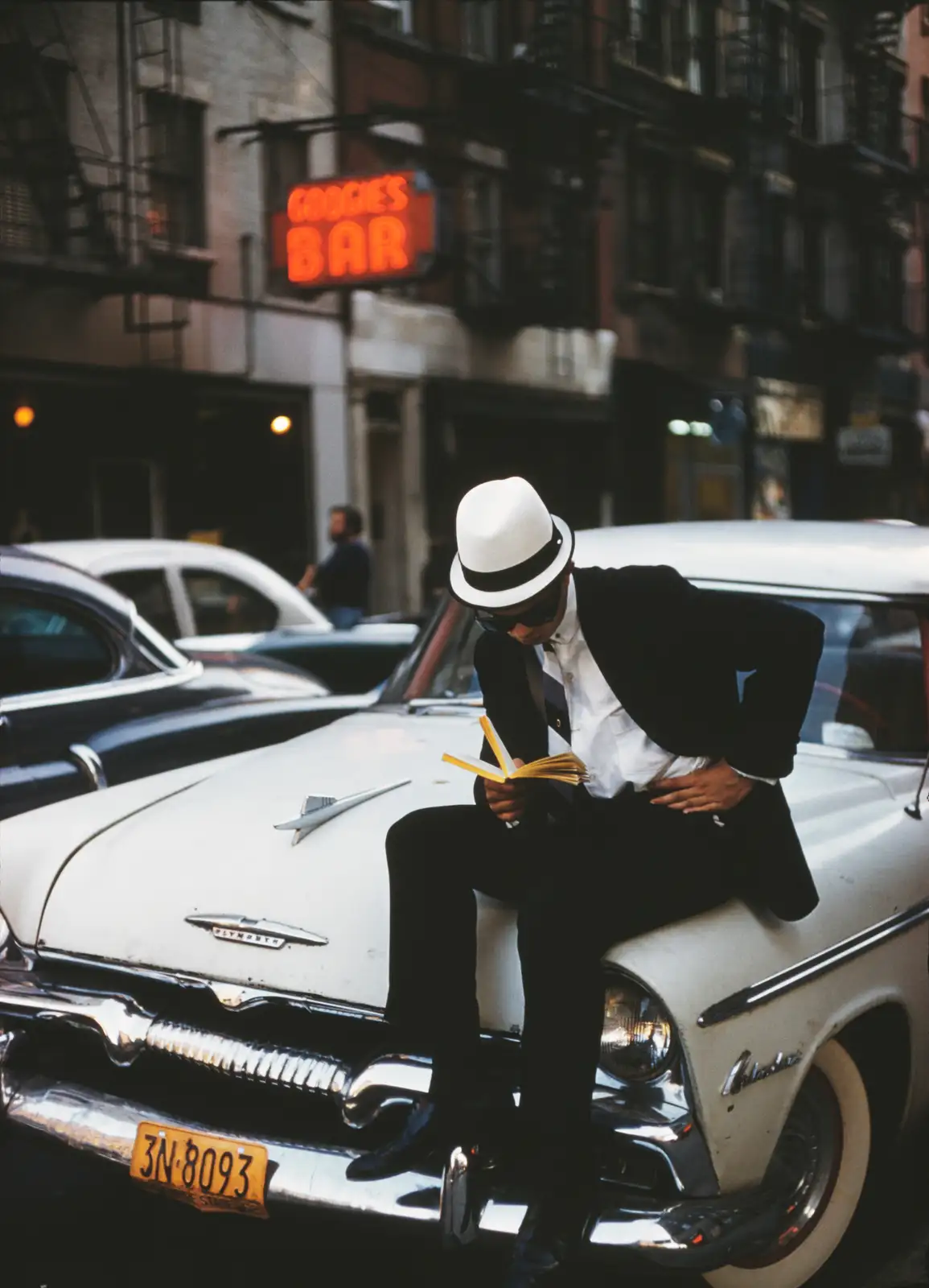 Ernst Haas, Man with white Hat reading on a car, NYC, 1952