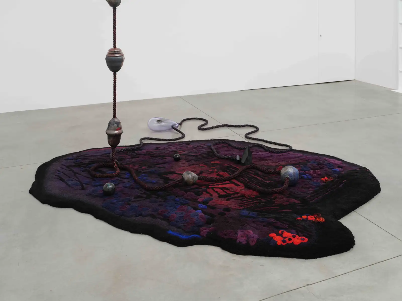 Otobong Nkanga, 'We Come from Fire and Return to Fire', 2024. Hand tufted carpet, glazed and smoked raku ceramic, shungite, tourmaline, handmade rope, metal connectors, 720 x 270 x 340 cm &copy; Otobong Nkanga, Courtesy Lisson Gallery.
