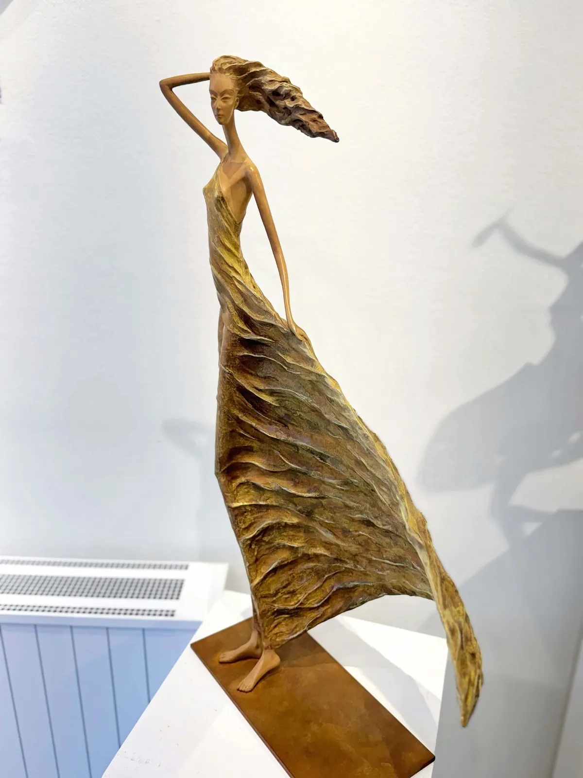 Alizé, een gouden sculptuur van een vrouw, geïnspireerd op Hedwige Leroux: een mooi jong meisje, vrij in de wind in een gouden jurk. Deze hedendaagse bronzen sculptuur is een figuratief kunstwerk en is te zien in de Art Yi-galerie in Brussel.