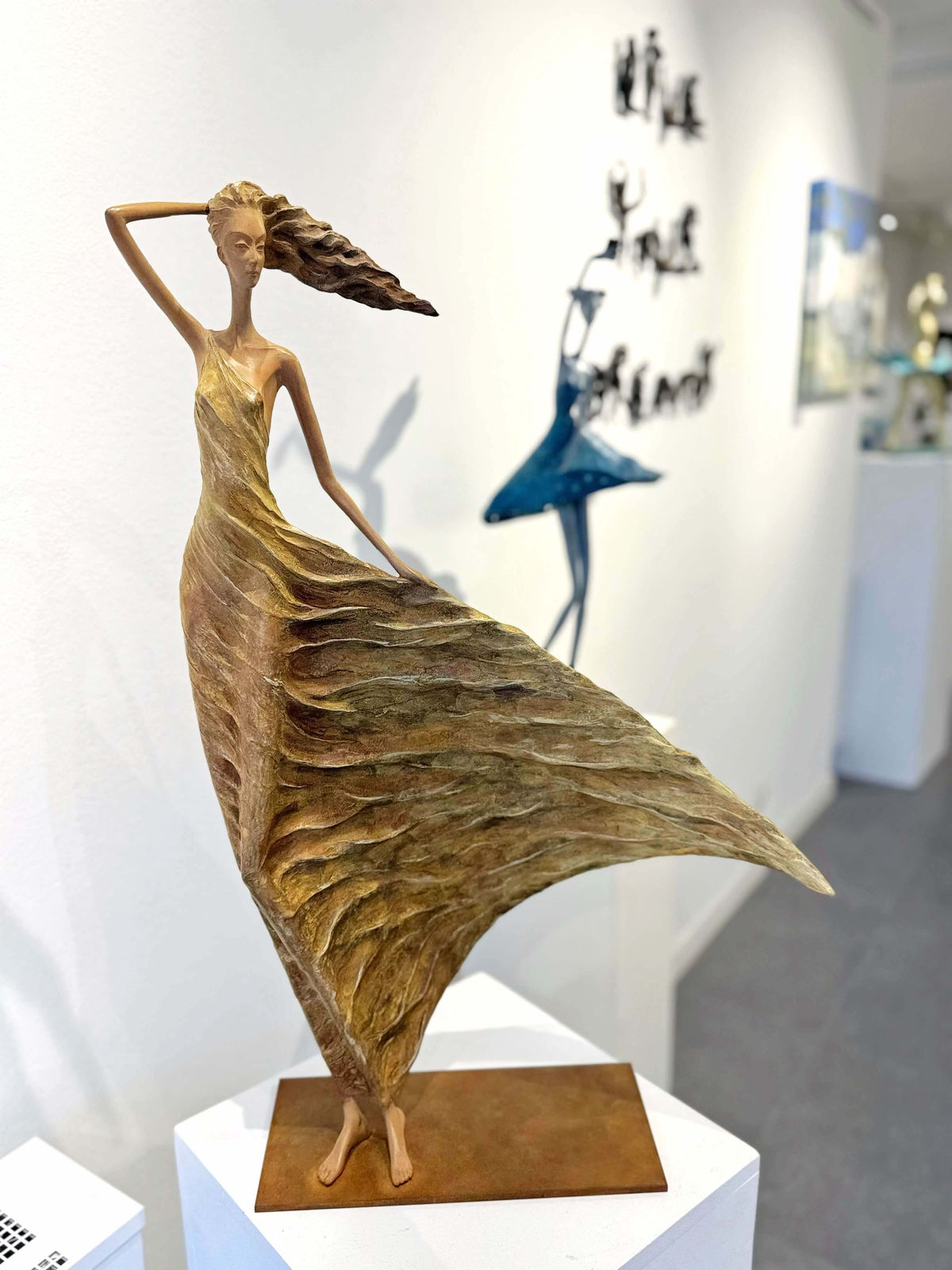 Escultura de Alizé, una mujer dorada que representa a Hedwige Leroux: una hermosa joven libre al viento con un vestido dorado. Escultura figurativa contemporánea en bronce, expuesta en la galería Art Yi de Bruselas.