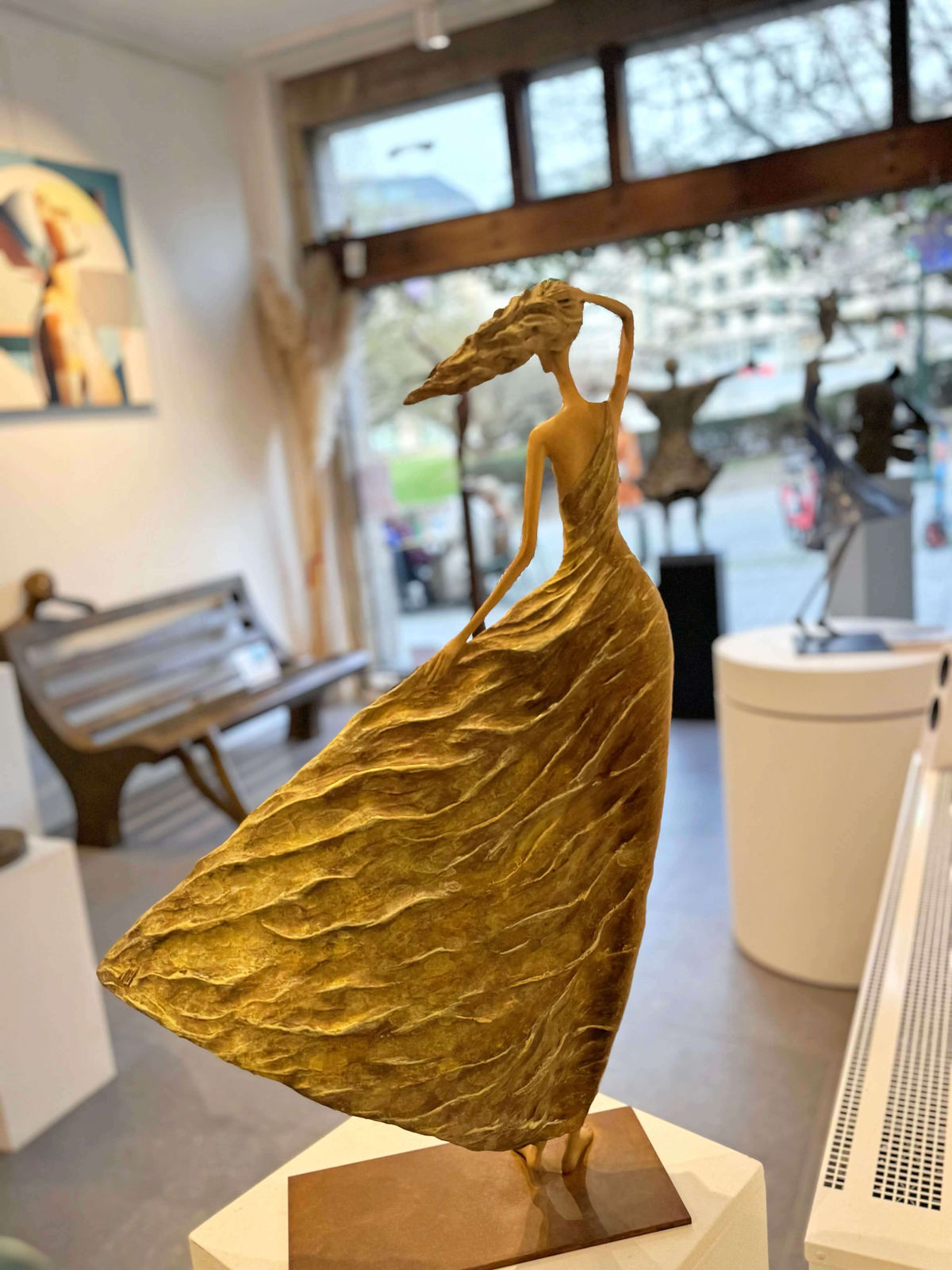 Escultura de Alizé, una mujer dorada que representa a Hedwige Leroux: una hermosa joven libre al viento con un vestido dorado. Escultura figurativa contemporánea en bronce, expuesta en la galería Art Yi de Bruselas.