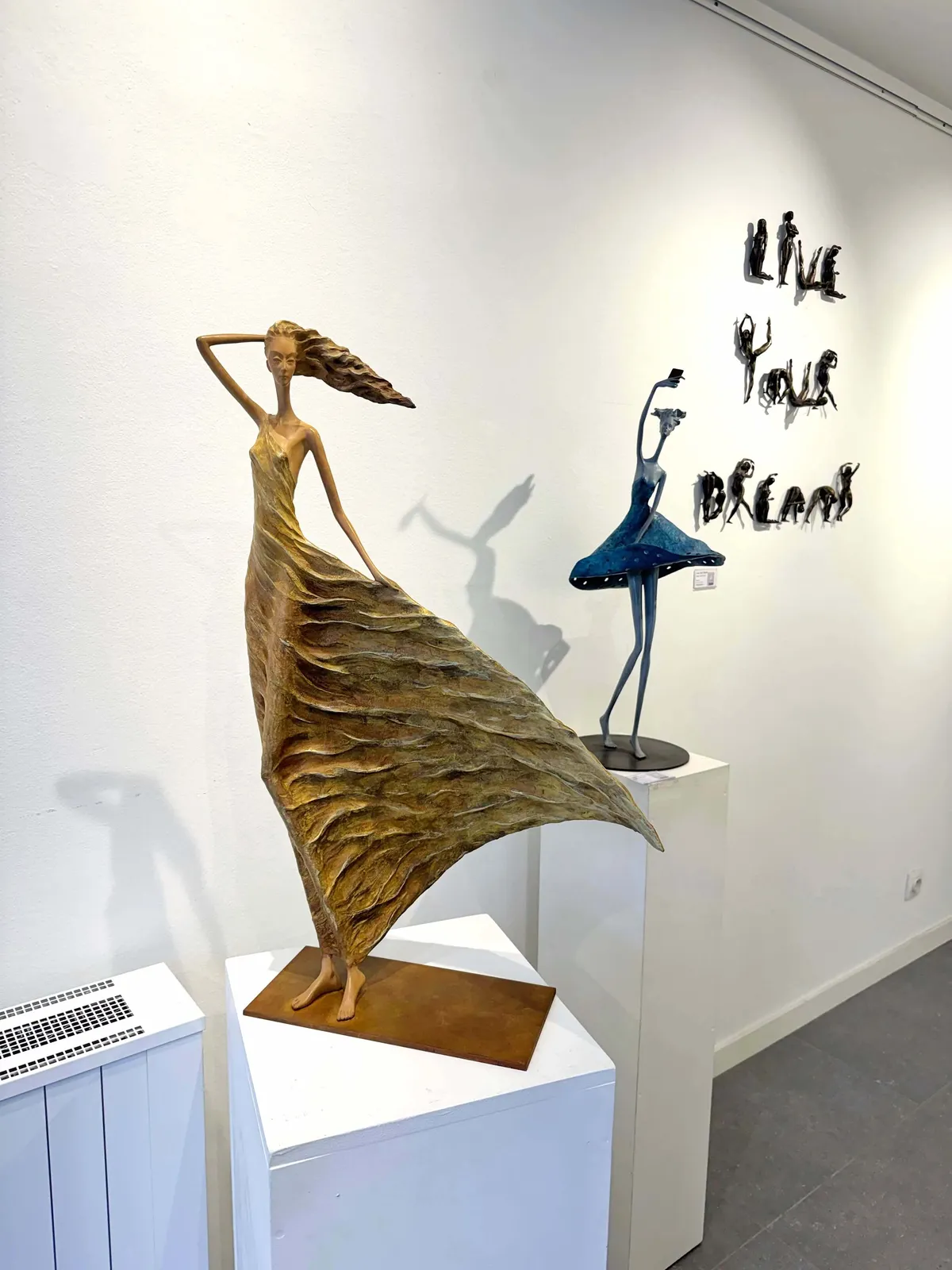 Alizé golden woman sculpture of Hedwige Leroux a beautiful young girl free in the wind in a a golden dress contemporary bronze sculpture figurative art at Art Yi gallery in Brussels