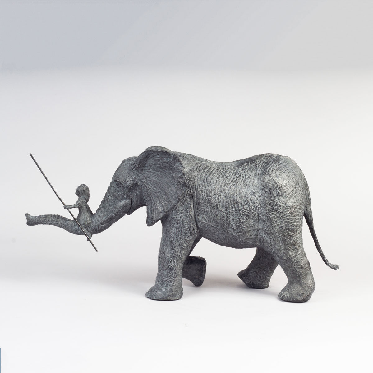 De avontuurlijke olifantensculptuur van Sophie Verger, een klein meisje dat op een olifant rijdt en samen een avontuurlijk, schattig dierenbeeldje van brons toont. Art Yi Gallery in Brussel.