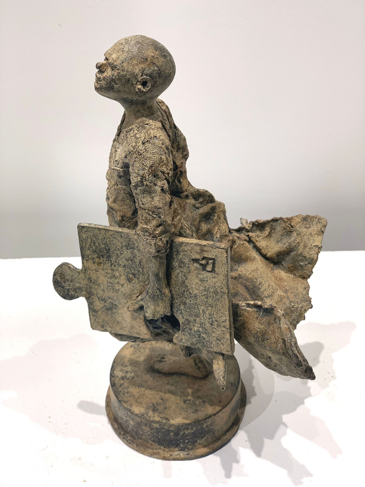 Missing link lieven d'haese contemporary bronze sculpture a boy running with a puzzle sculpture child sculpture childhood Art Yi art gallery in brussels