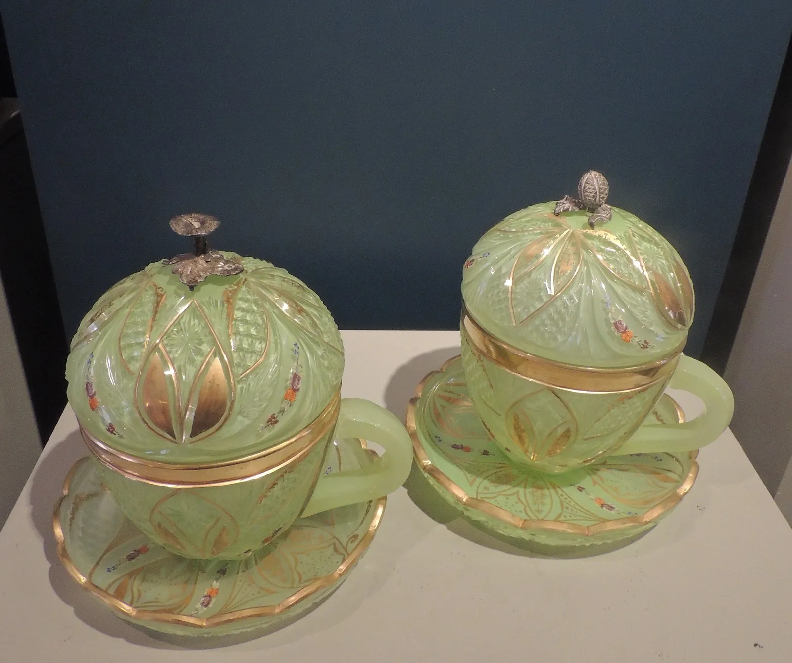 Pair of green glass lidded bombonieres, with silver floral knobs